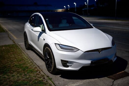 A white electric vehicle parked on an empty street in Garešnica at night.
