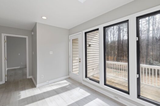 Spacious and bright room with large glass windows overlooking a serene outdoor setting.